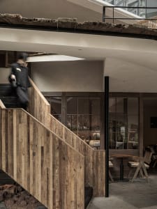 A warm and inviting staircase in a restaurant with a wooden railing and a person walking up the stairs