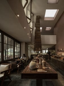 Cozy modern dining space with wooden feature, multiple tables, chairs, and dim lighting
