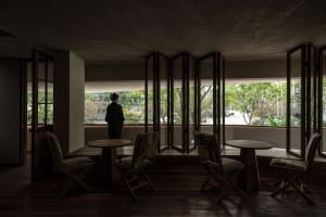 A modern restaurant interior with wooden floors and walls, featuring multiple tables and chairs, and two people in the scene, creating an inviting and comfortable atmosphere
