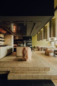 Modern kitchen with a large rock centerpiece, black countertops, and wine glasses, featuring a contemporary design and inviting atmosphere