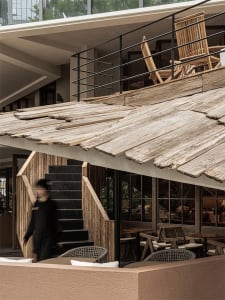 A casual dining area with wooden tables and chairs, backpacks on some chairs, and an inviting atmosphere
