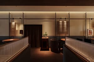 A modern restaurant dining area with tables, chairs, potted plants, artwork on the walls, and a stylish atmosphere