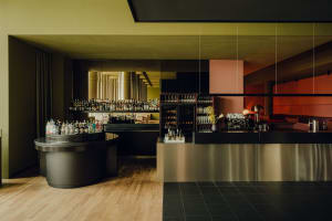 A lively bar scene with a wooden counter, wine glasses, and cups, set in a restaurant with a social atmosphere
