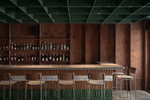 A modern bar with a counter and stools, surrounded by bottles and giving off a stylish and inviting atmosphere