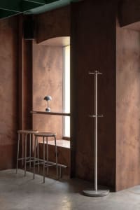 Warm and cozy interior space with brown wooden walls, metal stools, and a window, featuring a sink area that may be part of a kitchen or bathroom setup