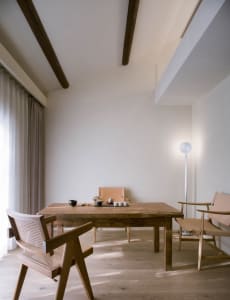Cozy dining space with a wooden table surrounded by chairs, featuring a vase and various tableware
