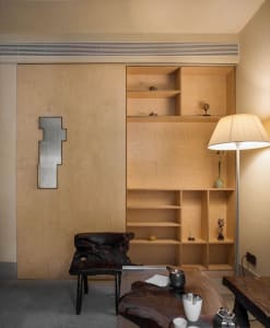 A well-lit room with a wooden bookshelf, chair, and lamp, creating a cozy atmosphere with warm wooden elements