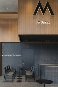 A modern coffee shop interior with a wooden counter and four chairs, creating a warm and inviting atmosphere