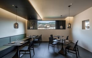 Empty restaurant with multiple dining tables and chairs in various styles, ready for guests
