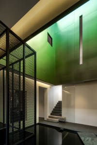 A modern house with green walls, a concrete staircase, and a glass door at the bottom of the stairs