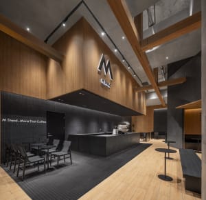 A modern coffee shop with a large open area featuring wooden floors and walls, comfortable seating, and dining tables