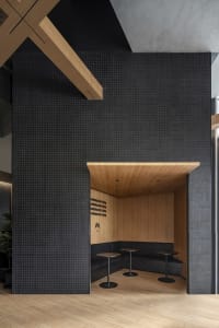 Modern restaurant dining area with black tile walls, multiple tables, and chairs, creating a sophisticated and inviting atmosphere