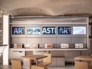 Modern art gallery with glass walls, TV screens, and minimalist decor, well-lit for art appreciation