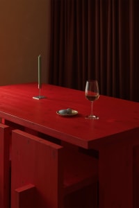 A cozy dining space with a wooden table, wine glasses, and a bowl, set in a warm and inviting atmosphere