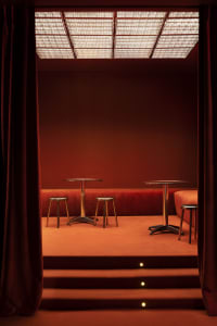 A warm and inviting dining space with two tables and four chairs, surrounded by red walls and a cozy atmosphere