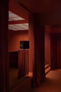 Cozy living space with orange walls, red curtains, a couch, two chairs, and two speakers for a relaxing atmosphere