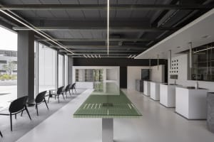 Modern open concept kitchen and dining area with a glass-topped island, white tile flooring, and sleek furniture