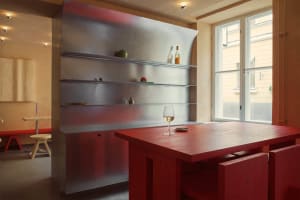 A cozy dining space with a wooden table, chairs, a wine glass, and fresh fruits, set in a warm and inviting atmosphere