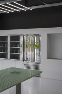 Modern kitchen with a stainless steel refrigerator, a table, and lined up cups on the countertop