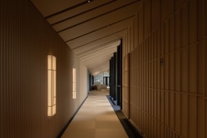 Empty hallway with wooden walls and flooring, lit by two lights on either side