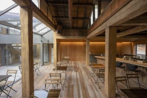 Warm and inviting restaurant interior with wooden floors and walls, featuring multiple dining tables and chairs, creating a cozy atmosphere