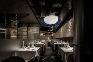 Empty restaurant with dining tables and chairs, wine glasses on some tables, inviting atmosphere