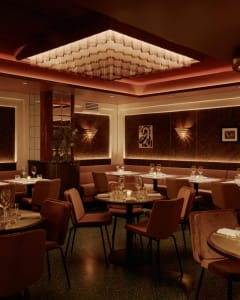 Sophisticated dining space with brown tables and chairs, wine glasses, and well-lit areas
