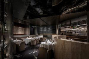Sophisticated dining area with white tablecloths, utensils, and wine glasses, set amidst a comfortable and inviting atmosphere