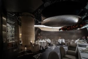 Dimly lit restaurant interior with wooden tables and chairs, vases, and a cozy atmosphere