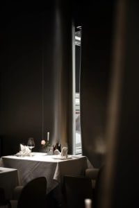 A dining area with a wooden table, two chairs, a vase, and various tableware, set in an elegant and inviting atmosphere
