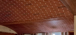 A traditional brick building with a red roof, featuring bricks on the walls and possibly some wood elements, with natural light coming through windows or openings