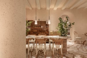A modern kitchen with a dining table, wooden cabinets, and countertops, surrounded by potted plants and featuring ample storage and workspace