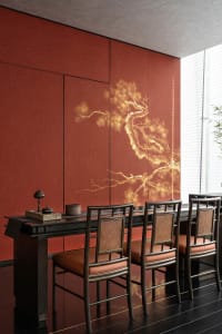 Dining area with red walls, a wooden table, and four chairs, featuring a vase and warm lighting