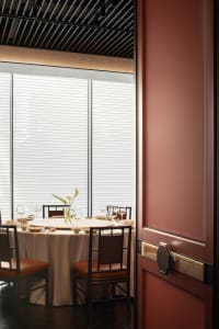 A luxurious dining area with a wooden table and chairs, wine glasses, and decorative vases, set in a sophisticated restaurant environment