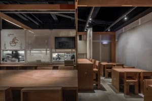 Warm kitchen space with wooden floors and walls, featuring a dining table and chairs, appliances, and a comfortable seating arrangement