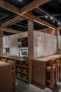 A bustling restaurant kitchen with wooden walls and floors, featuring countertops, ovens, and various kitchen items