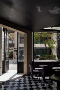 Modern restaurant interior with tables, chairs, bar, potted plants, artwork, and modern design