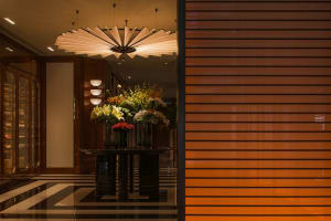 A well-lit room with a large black table, potted plants, and a vase of flowers, creating a warm and inviting atmosphere