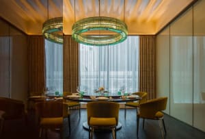 A dining area with a round table set with wine glasses, cups, and vases, surrounded by chairs in a sophisticated and comfortable environment