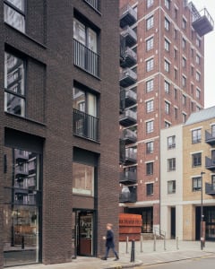 A bustling city street scene with tall brick buildings, pedestrians, and diverse architectural styles