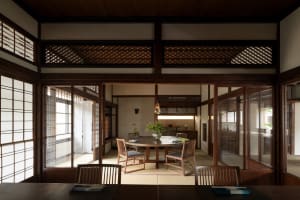 A warm and inviting dining area with a wooden table and chairs, featuring a vase on the table and a traditional Asian aesthetic