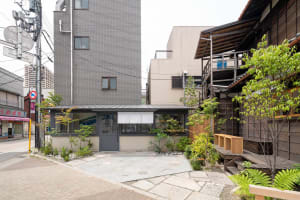 A city scene with a brick building and a modern building next to each other, featuring balconies and potted plants