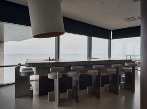 Bright and inviting kitchen with a modern design, featuring a large island countertop with stools and a sink, and natural light coming in through windows