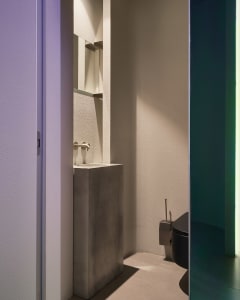 A modern bathroom with a sink, toilet, and shower area, featuring clean lines, minimalistic elements, and white walls creating a bright and airy atmosphere