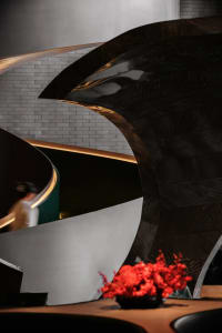 A modern interior space with a spiral staircase made of metal, featuring a person walking up the stairs while another person stands at the bottom