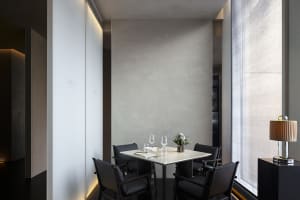 Elegant dining space with a large wooden table and chairs, set with four wine glasses, in a restaurant atmosphere