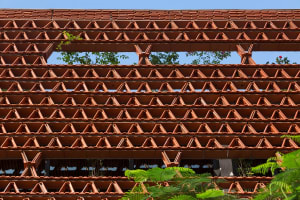 A brick building with many windows, surrounded by potted plants, conveying a sense of urban architecture and design
