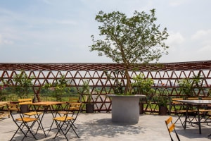 A relaxed outdoor patio area with stone tables, umbrellas, and potted plants, perfect for dining or conversation