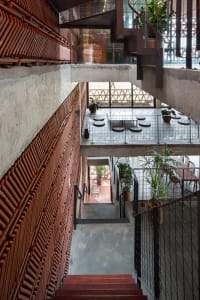 A modern stairwell with concrete stairs, well-lit and decorated with potted plants and chairs, creating a comfortable seating area