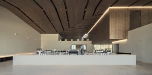 A bright and inviting restaurant dining area with a large wooden table and chairs, surrounded by cups and offering ample seating for patrons